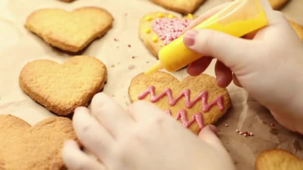 Mulher decora biscoitos em forma de coração com gelo amarelo, close-up, processo de cozimento, conceito romântico — Vídeo de Stock