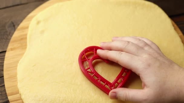 Kadın hamurdan kalp şeklinde kurabiyeler kesiyor, eller yakın plan, tatlı pişirme süreci — Stok video