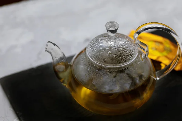 Стеклянный чайник с горячим зеленым чаем на подносе на столе крупным планом — стоковое фото