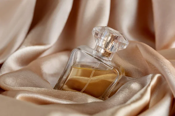 Скляна пляшка парфумів на золотому шовковому фоні — стокове фото