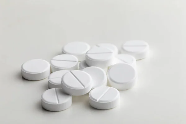 A handful of round white pills on a white table close-up, macro, medical background — Stock Photo, Image