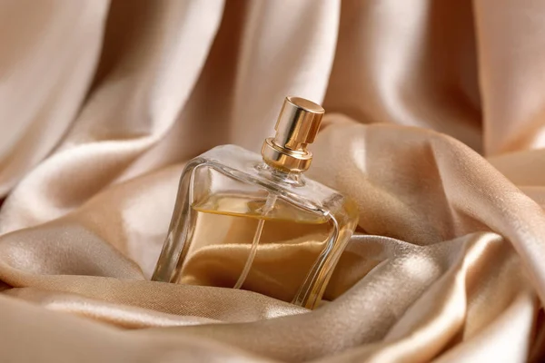 Glass bottle of perfume without a lid on a background of golden silk, the concept of expensive perfume and cosmetics — Stock Photo, Image