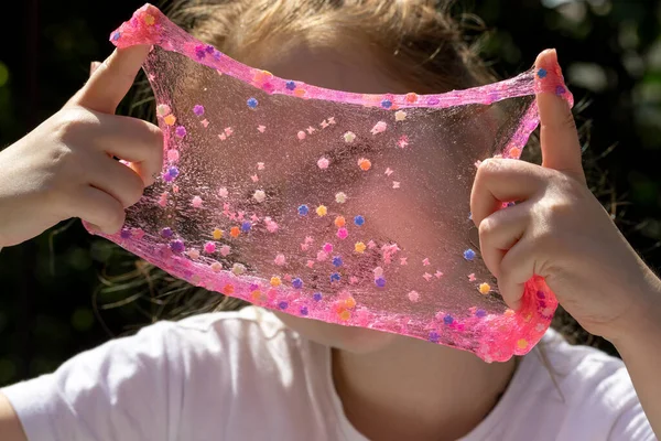 Küçük kız şeffaf pembe sümüksü süslemeler sergiliyor.