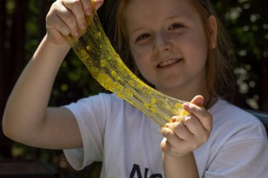 Küçük bir kız sümük yapmış ve onunla oynamış, onu germiş ve şeffaf bir balçık dokusunu süslemiş.