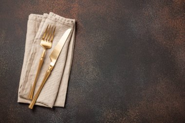 Paslanmış metalik yüzeyde altın çatal bıçak takımı olan masa yeri