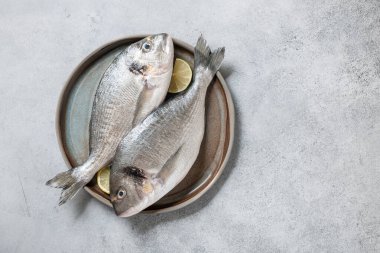 Seramik tabakta taze dorado balığı pişirmek için.