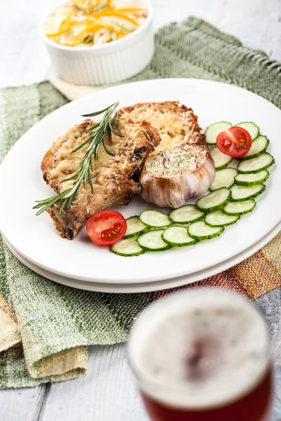 Piatto di braciole di maiale e bicchiere di birra — Foto Stock