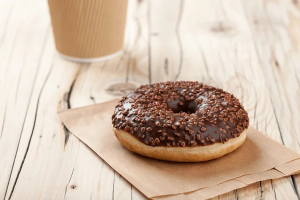 Donut e xícara de papel na mesa de madeira — Fotografia de Stock