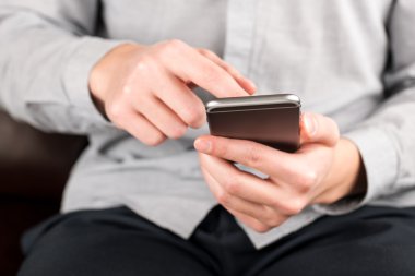 Genç adam akıllı telefon kullanıyor.