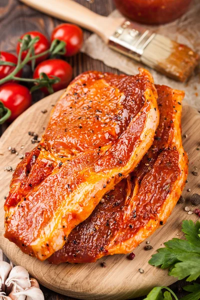 Kesme tahtası üzerinde marine edilmiş domuz eti biftek