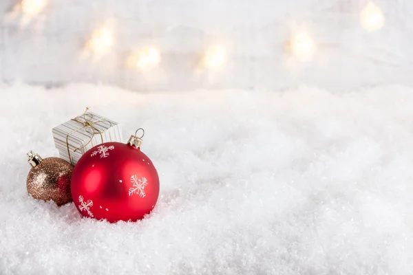 Weihnachtskugeln und Geschenkschachtel auf Schnee — Stockfoto