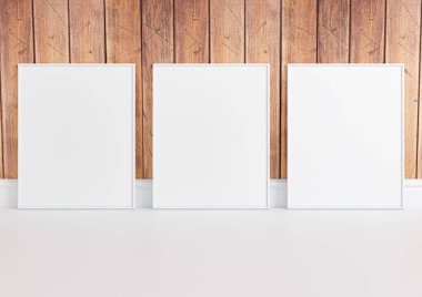 Üçlü 8x10 dikey beyaz çerçeve modeli beyaz zeminde ve kırsal ahşap duvarda. Beyaz zeminde ve ahşap arka planda üç boş poster modeli. 3B Hazırlama
