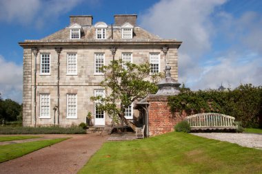 Kırsaldaki tipik bir İngiliz kır evi. Geniş çimleri ve süslemeleri olan geniş bir bahçesi var.