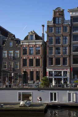 Amsterdam kanal kemerinde sokak hayatı ve mobilyalarla tipik Hollanda mimari binaları