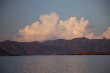Gün batımı altında dağları olan güzel bir göl.