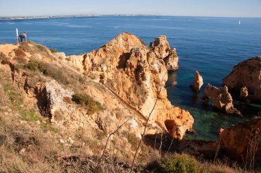 Tipik ve turistik engebeli ve çökmekte olan dengesiz Algarve kayalık kıyıları denizlerde kayalık tepeler, mağaralar, kemerler ve gizli cennet kumsalları