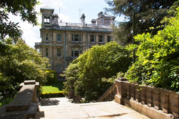 Typically English university landscape garden with hedges, fences, plant and flower beds, lawn and garden furniture