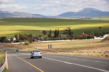 Yeşil dağlık alanda hareket eden arabaların olduğu yol