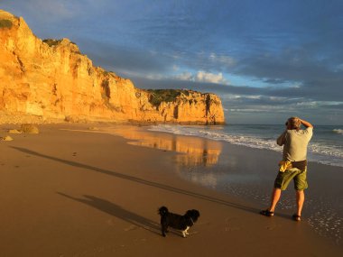 Sahilde fotoğraf çeken bir adam.