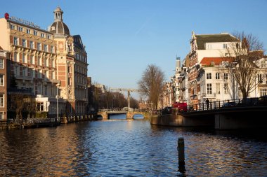 Amsterdam kanal kemerinde sokak hayatı ve mobilyalarla tipik Hollanda mimari binaları