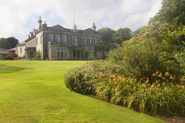 Bereketli yeşil çimlerin manzarası ve güneş ışığında eski bir bina.