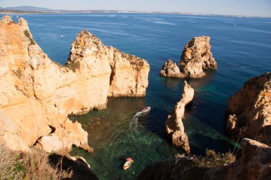 Tipik ve turistik engebeli ve çökmekte olan dengesiz Algarve kayalık kıyıları denizlerde kayalık tepeler, mağaralar, kemerler ve gizli cennet kumsalları