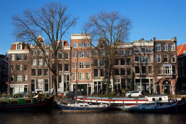 Amsterdam kanal kemerinde sokak hayatı ve mobilyalarla tipik Hollanda mimari binaları
