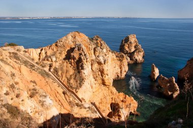 Tipik ve turistik engebeli ve çökmekte olan dengesiz Algarve kayalık kıyıları denizlerde kayalık tepeler, mağaralar, kemerler ve gizli cennet kumsalları