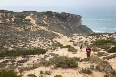 Sahilde yürüyen iki turist.