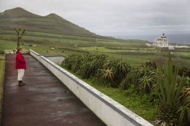 Kumsalda sırt çantalı kırmızı elbiseli bir kadın.