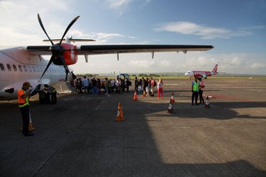 Havaalanında gün ışığında uçağı olan bir grup insan.