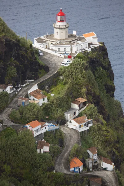 Etrafı doğal bulutlarla çevrili tarihi deniz feneri bir uçurumun tepesine ve limana uzanan dik erişim yoluna ışık hüzmesi veriyor.