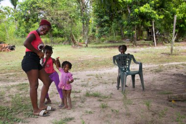 Dışarıda oynayan çocuklu siyah bir anne.