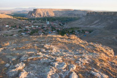 Tipik Kapadokyaca Vadisi köyü, taşlara kazınmış tarihi kaya konutları ve kiliselerle aşınmış dağın yanında.