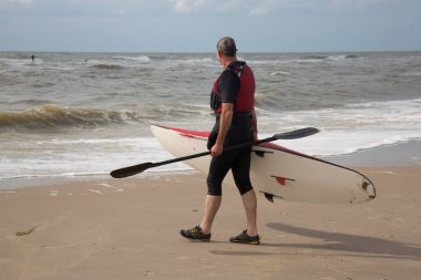 Deniz sahilinde kanolu bir adam.