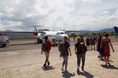 Havaalanında gün ışığında uçağı olan bir grup insan.