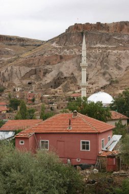 Tipik Kapadokyaca Vadisi köyü, taşlara kazınmış tarihi kaya konutları ve kiliselerle aşınmış dağın yanında.
