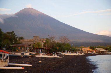 Sahilde demirlemiş kayıklar ve arka planda dağlar.