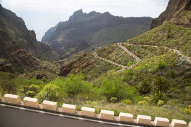 Yeşil dağları ve bulutlu gökyüzü olan güzel bir manzara.