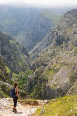 Sırt çantalı bir kadın dağda yürüyüş yapıyor.