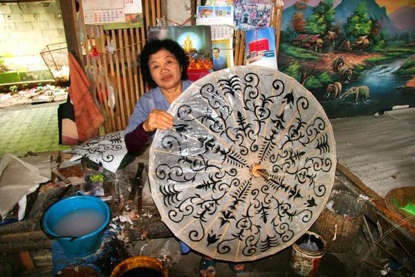 Atölyede şemsiye yapan yaşlı kadın.