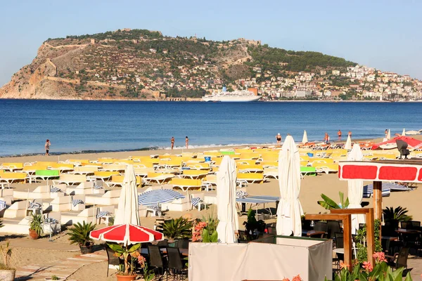 Güneşli halk plajı sahnesi ve denizdeki dağ