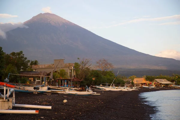 Sahilde demirlemiş kayıklar ve arka planda dağlar.