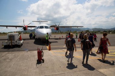 Havaalanında gün ışığında uçağı olan bir grup insan.