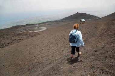 Sırt çantalı bir kadın yol ve dağ boyunca yürüyor, seyahat konsepti.