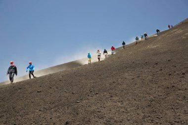 Volkanik tepelerde yürüyen bir grup insan
