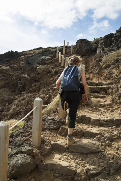 Deniz kenarındaki kayalık bir yolda yürüyen turistlerin görüntüsü