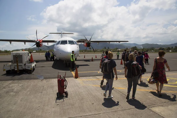 Havaalanında gün ışığında uçağı olan bir grup insan.