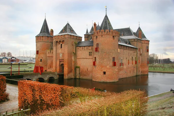 Bulutlu gökyüzünün altında havuzla çevrili eski bir kale binası.