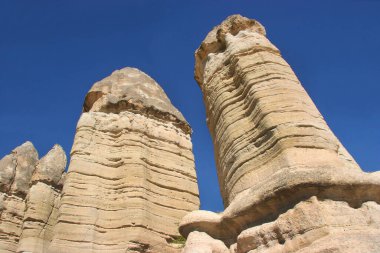 Aşınmış yüksek bacalar ya da tepeler, yukarıda dengelenen daha sert taşlar ve aşağıdan bakıldığında daha yumuşak sütunu kaplıyorlar.